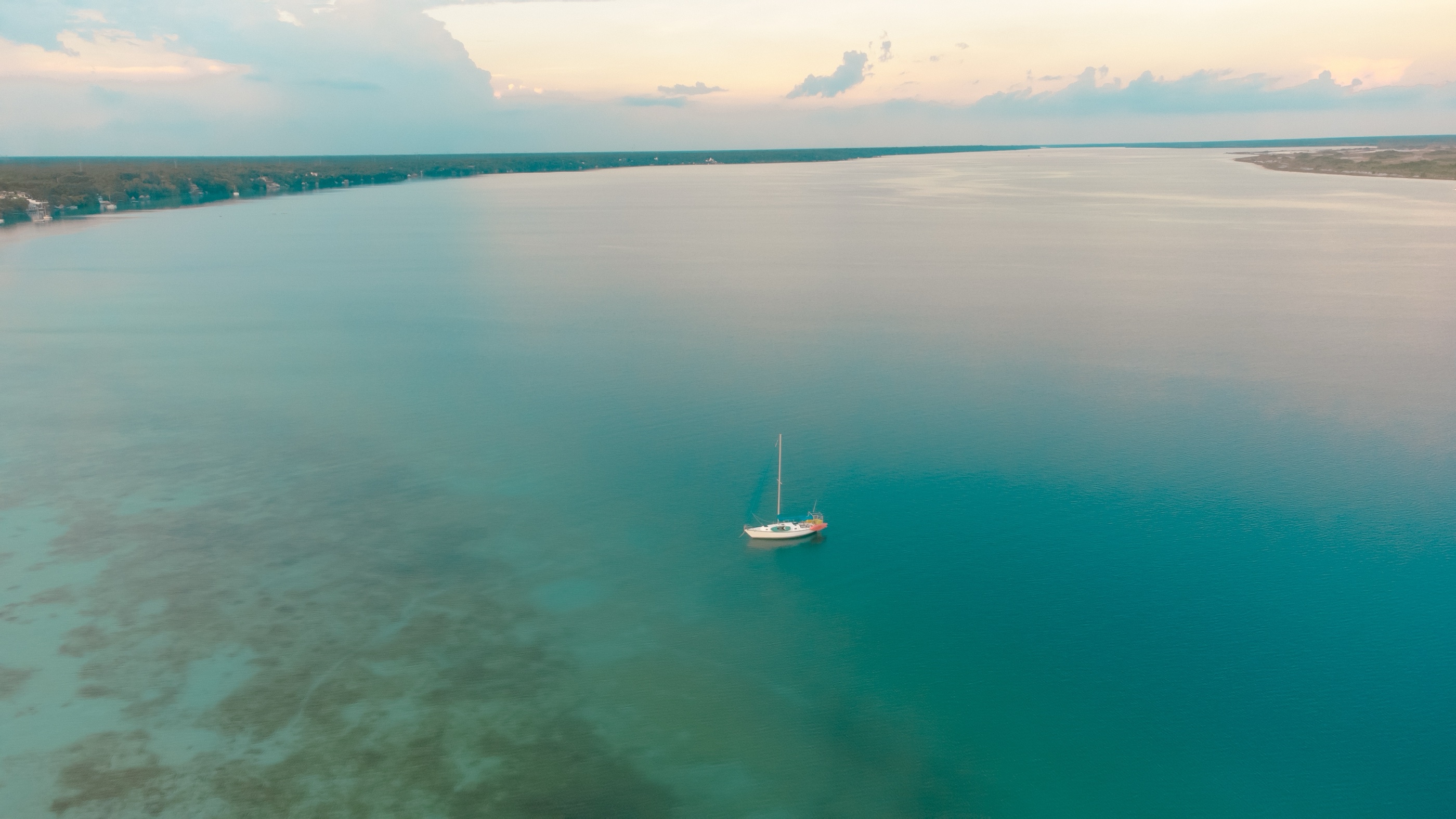 Velero anclado en las aguas turquesa de la laguna al atardecer.